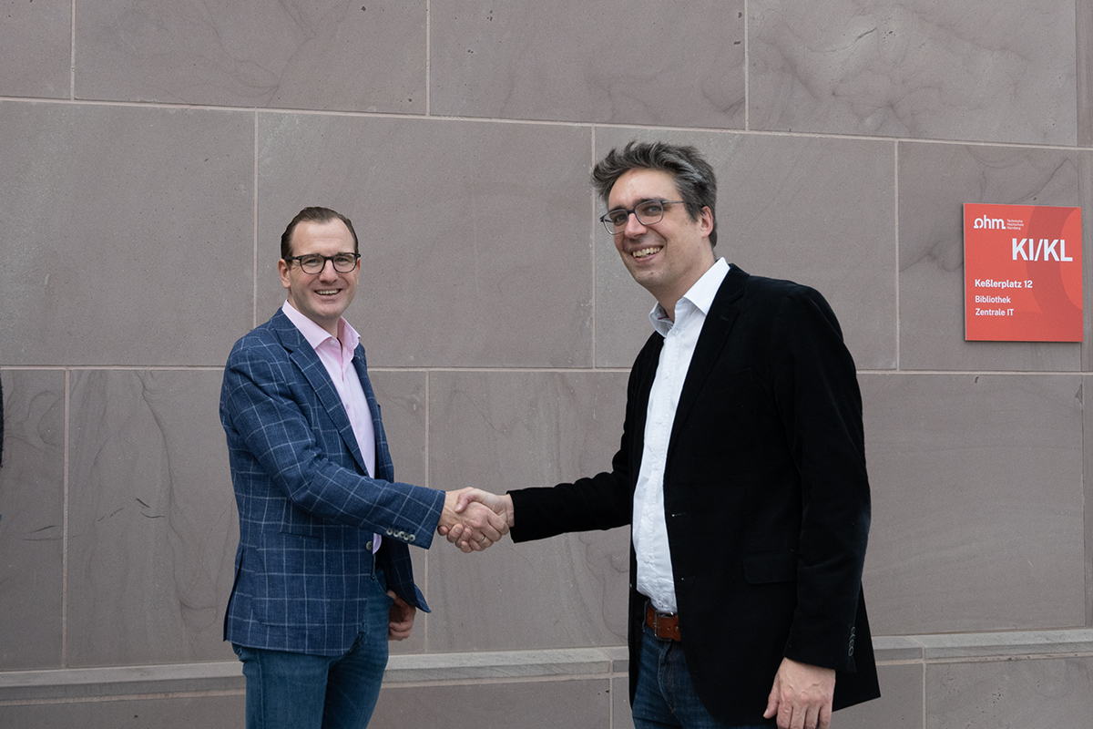 Das Bild zeigt Adrian Merkel, CEO der speedikon FM Group, wie er Prof. Dr. Thomas Voit vor der Technischen Hochschule Nürnberg die Hand gibt.